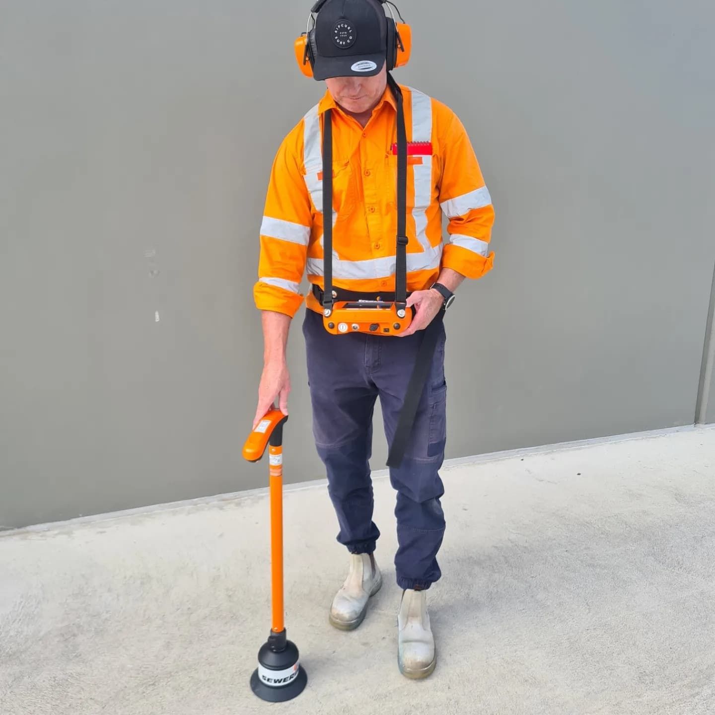 a man in high vis is holding water leak detection equipment — Dowds Pipe and Cable Locating in Farmborough Heights, NSW