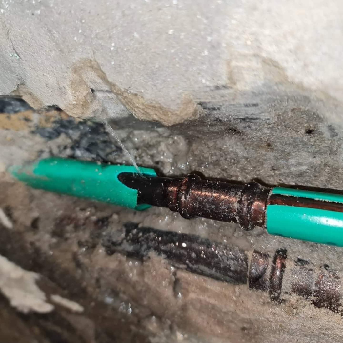 A Green Pipe is Coming Out of a Hole in the Wall — Dowds Pipe and Cable Locating in Manly, NSW