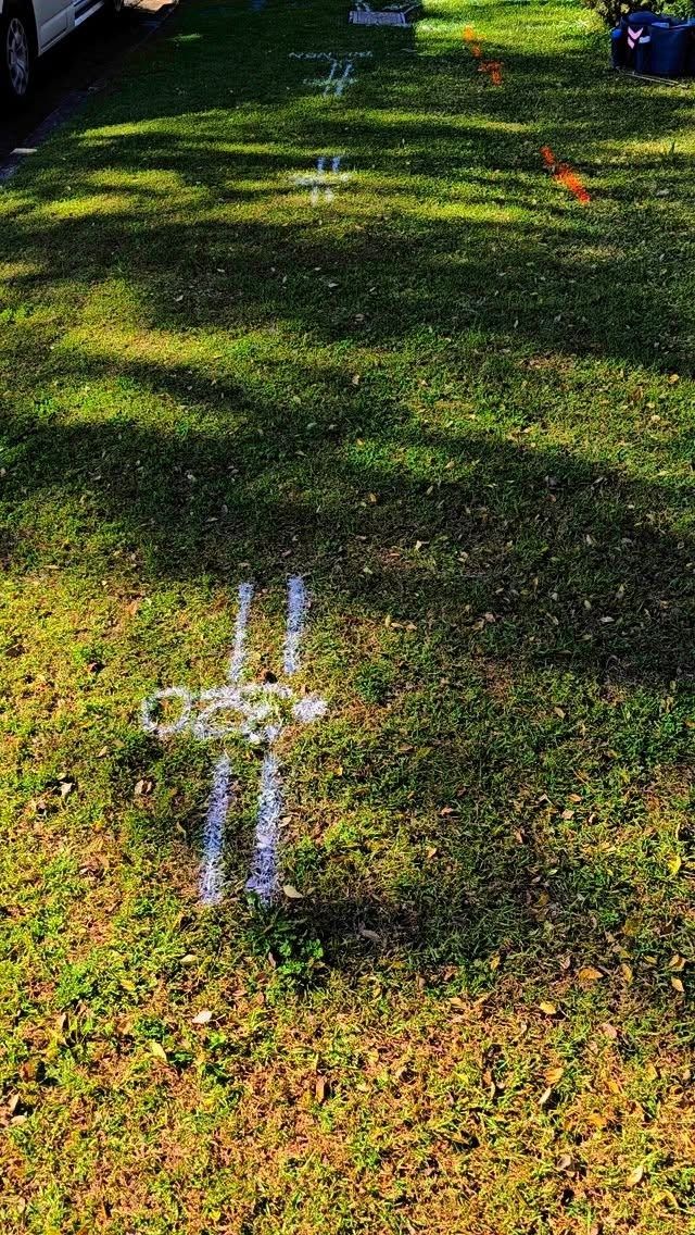 A Puddle of Water in the Grass With a Cross Drawn in It — Dowds Pipe and Cable Locating in Nowra, NSW