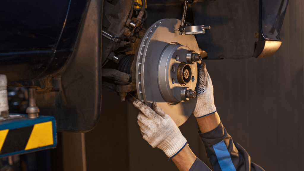 A man is fixing a brake on a car in a garage. | Karta Motorwerks