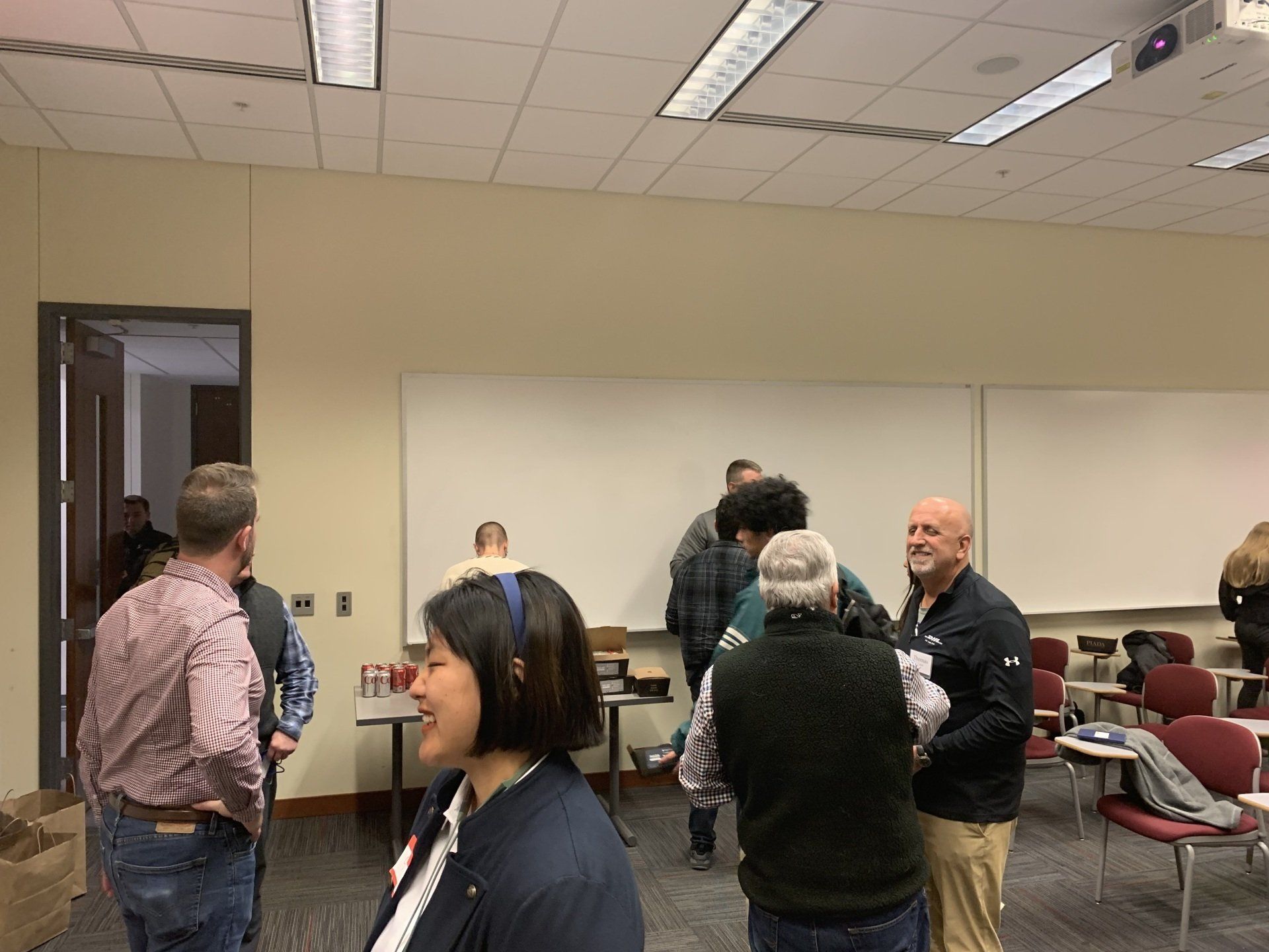 A group of people are standing in a room talking to each other