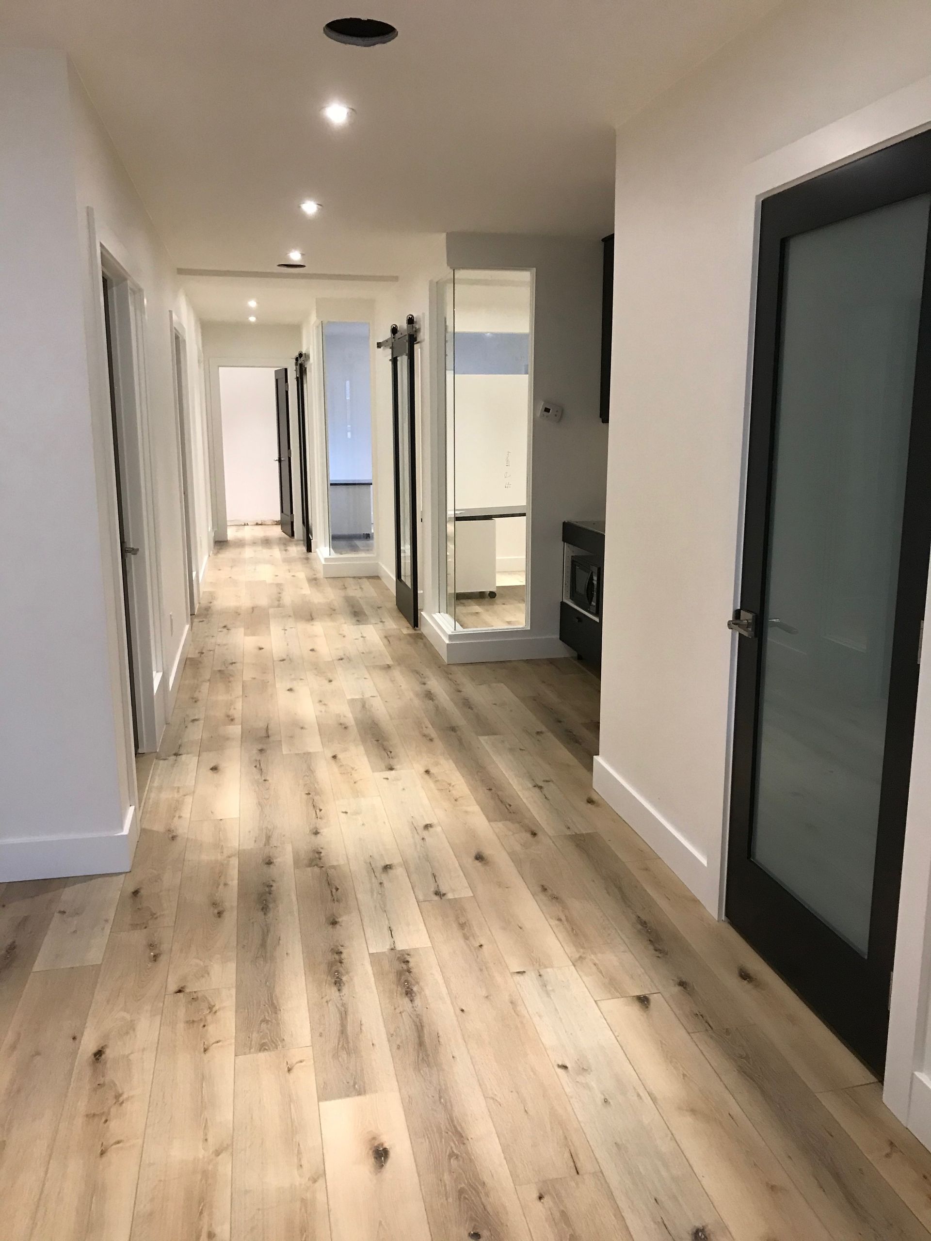 A long hallway with wooden floors and white walls.