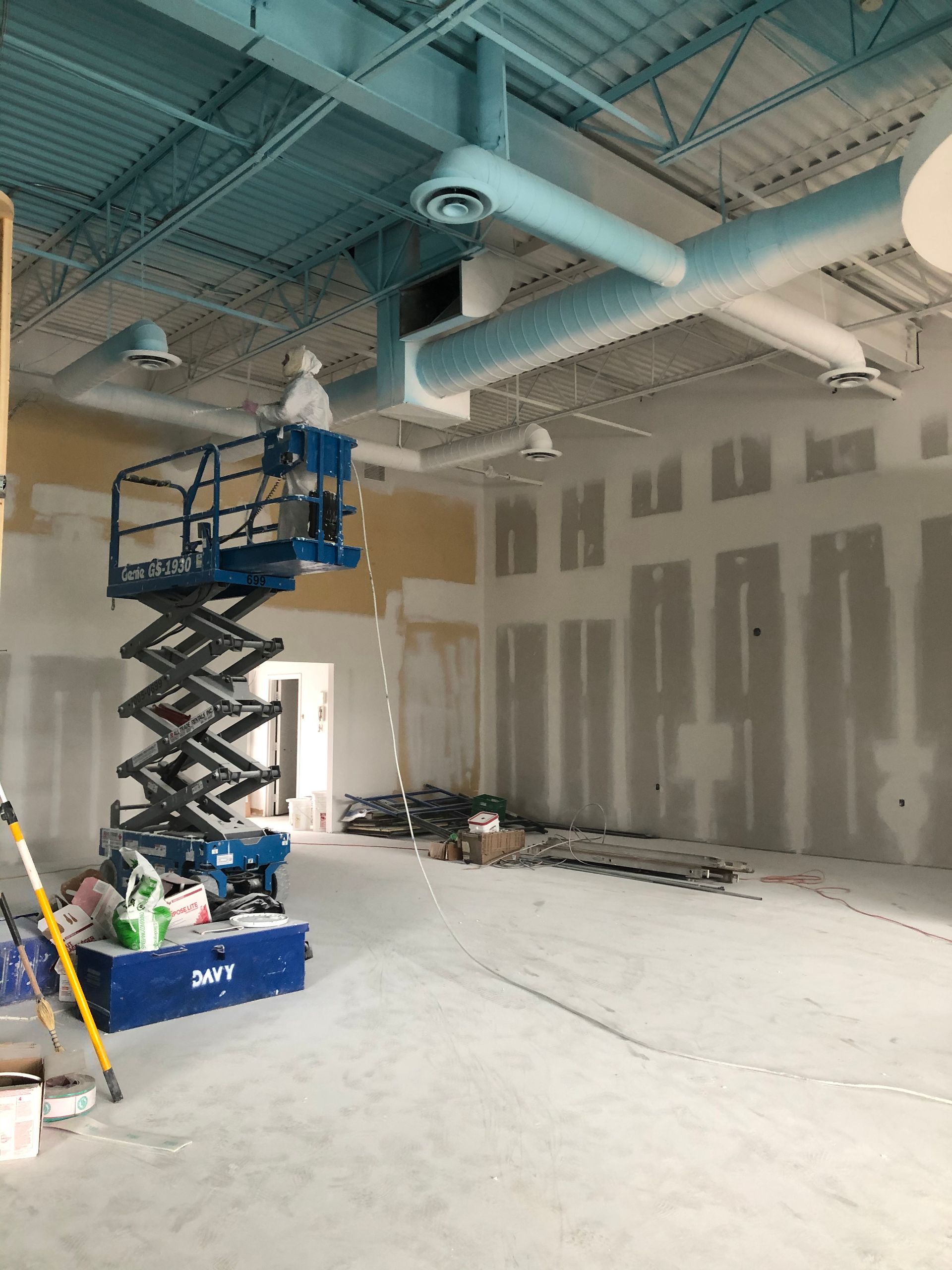 An empty room with a scissor lift in the middle of it.