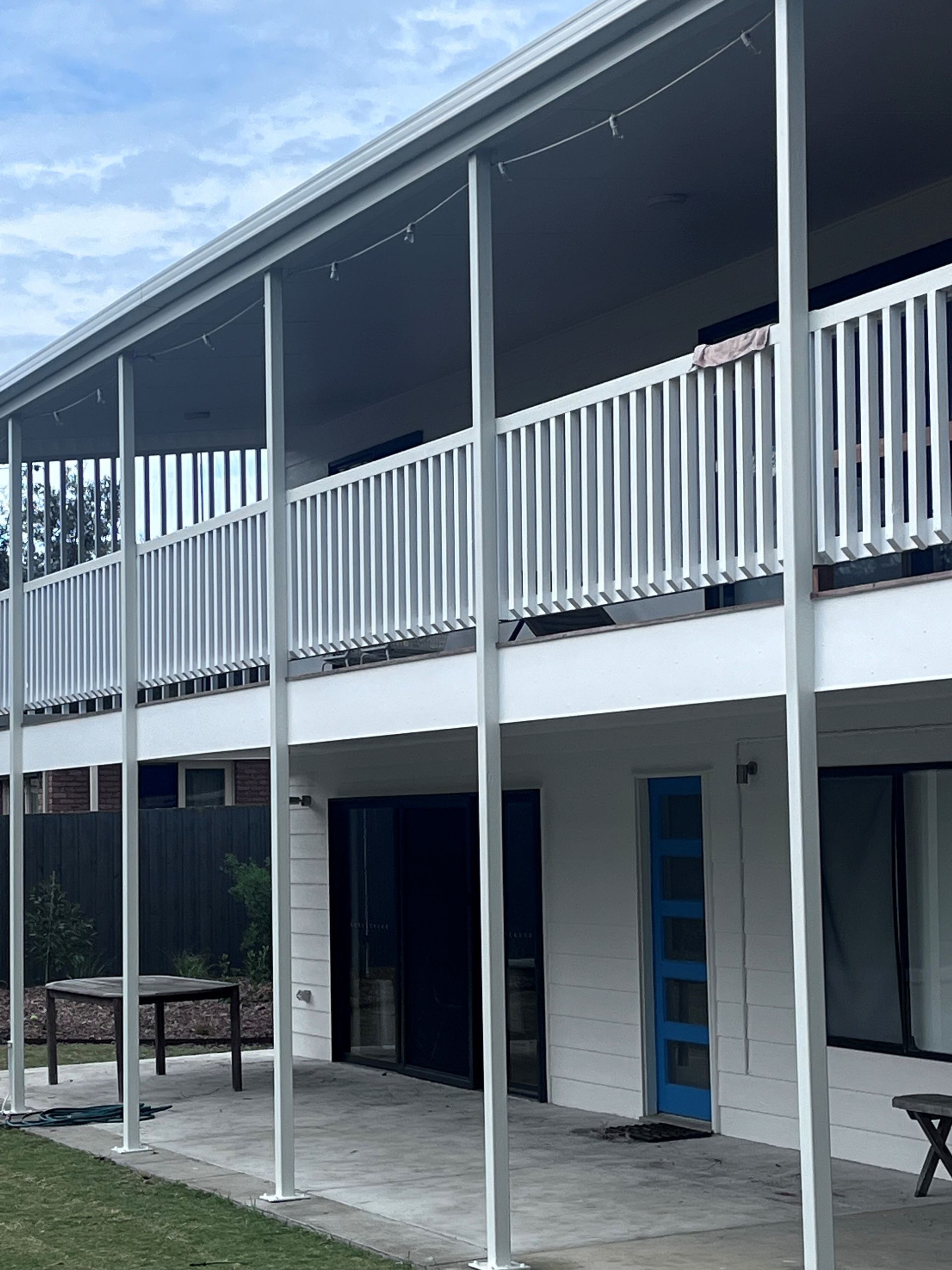 A white building with a balcony and a blue door