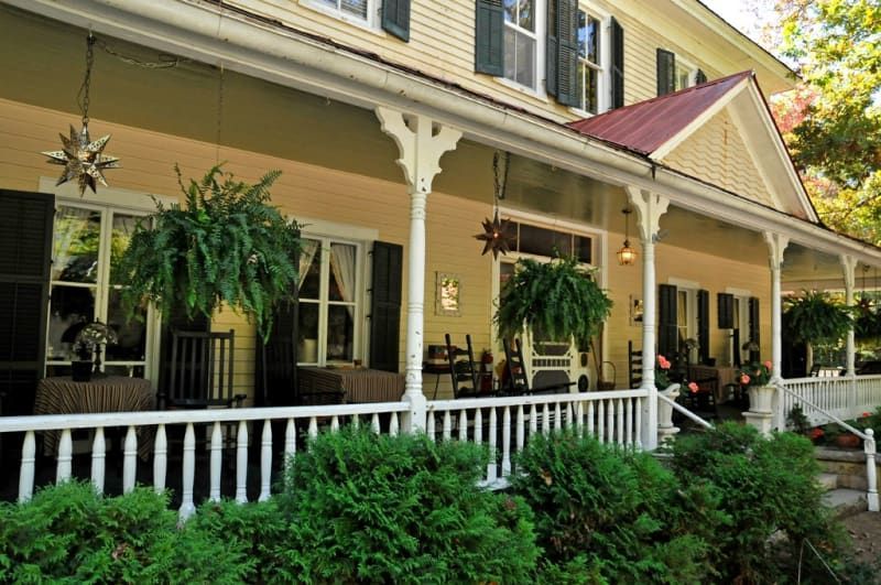 A large house with a porch and chairs on it.
