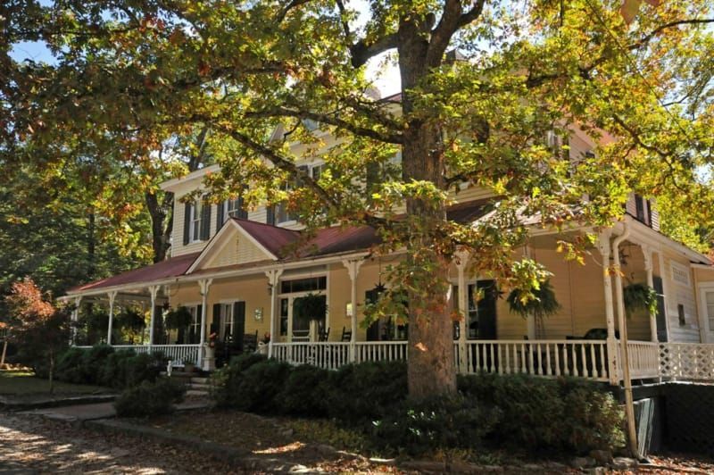 A large house with a large porch is surrounded by trees