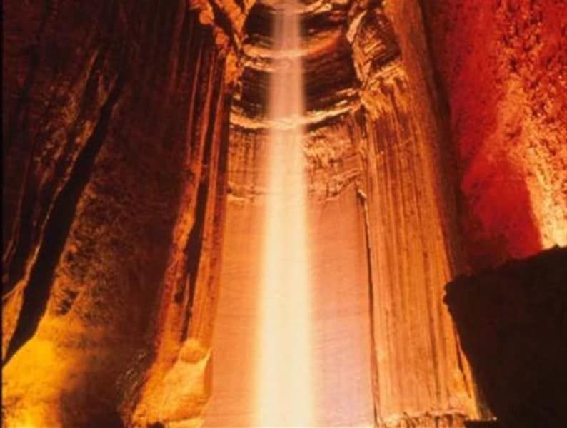 A waterfall in a cave with a light coming out of it