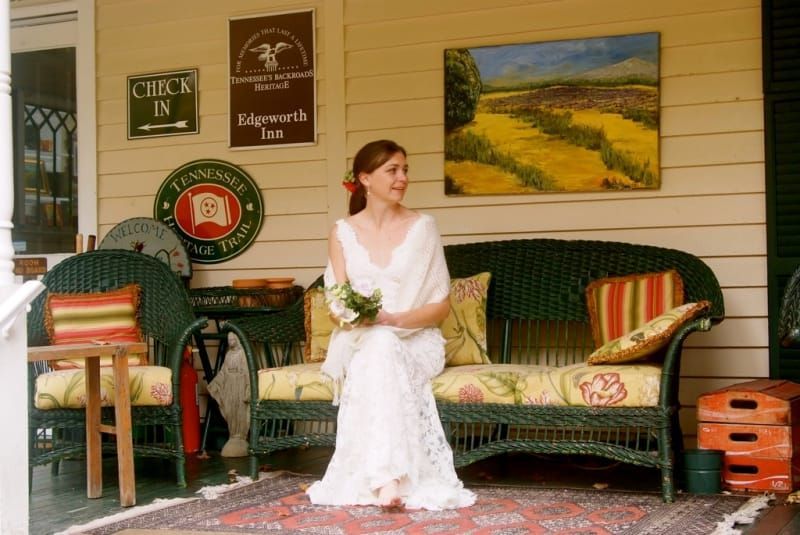 A woman in a white dress is sitting on a wicker couch