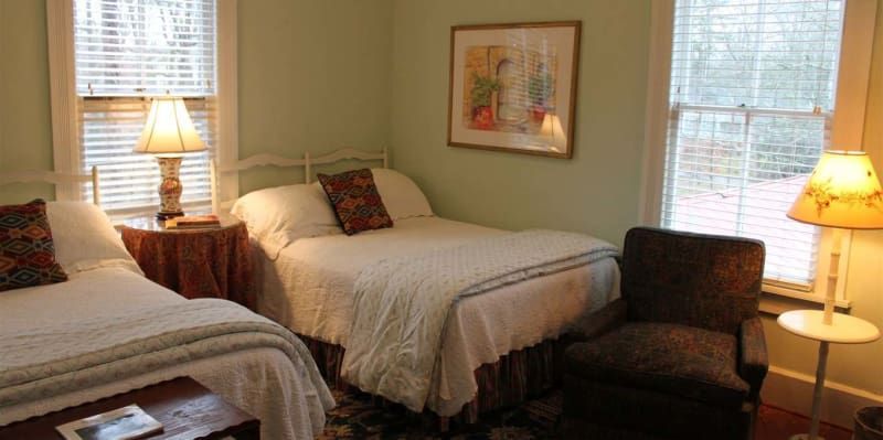 There are two beds and a chair in the room.
