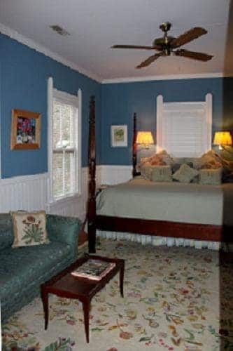 A bedroom with a bed , couch , table and ceiling fan.