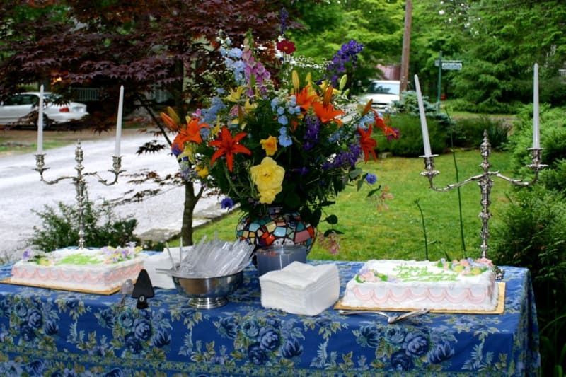 A table with two cakes and a vase of flowers on it