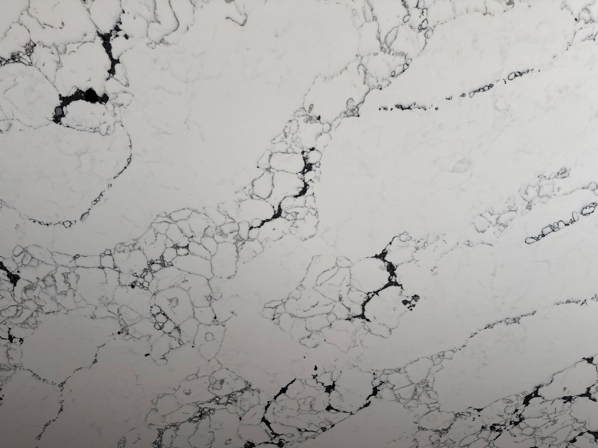 A close up of a white marble counter top with black spots.