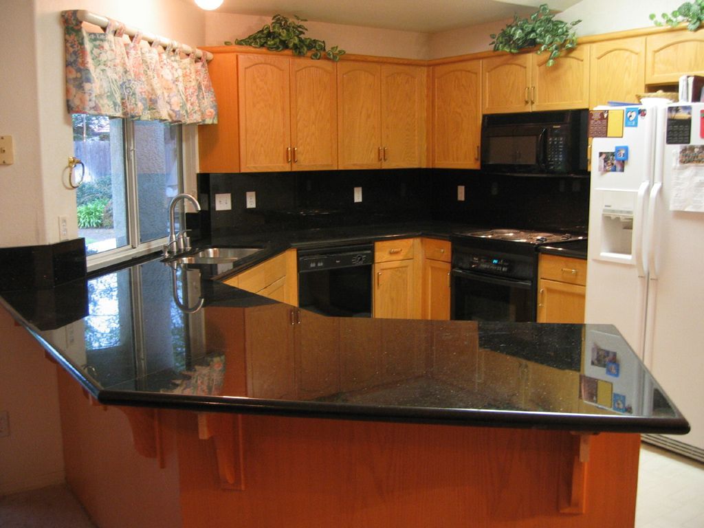 A kitchen with wooden cabinets and black counter tops