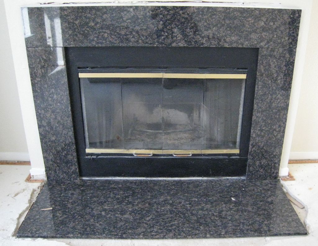 A fireplace with a black granite surround and gold trim