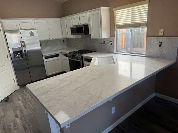 A kitchen with white cabinets and a large island in the middle.