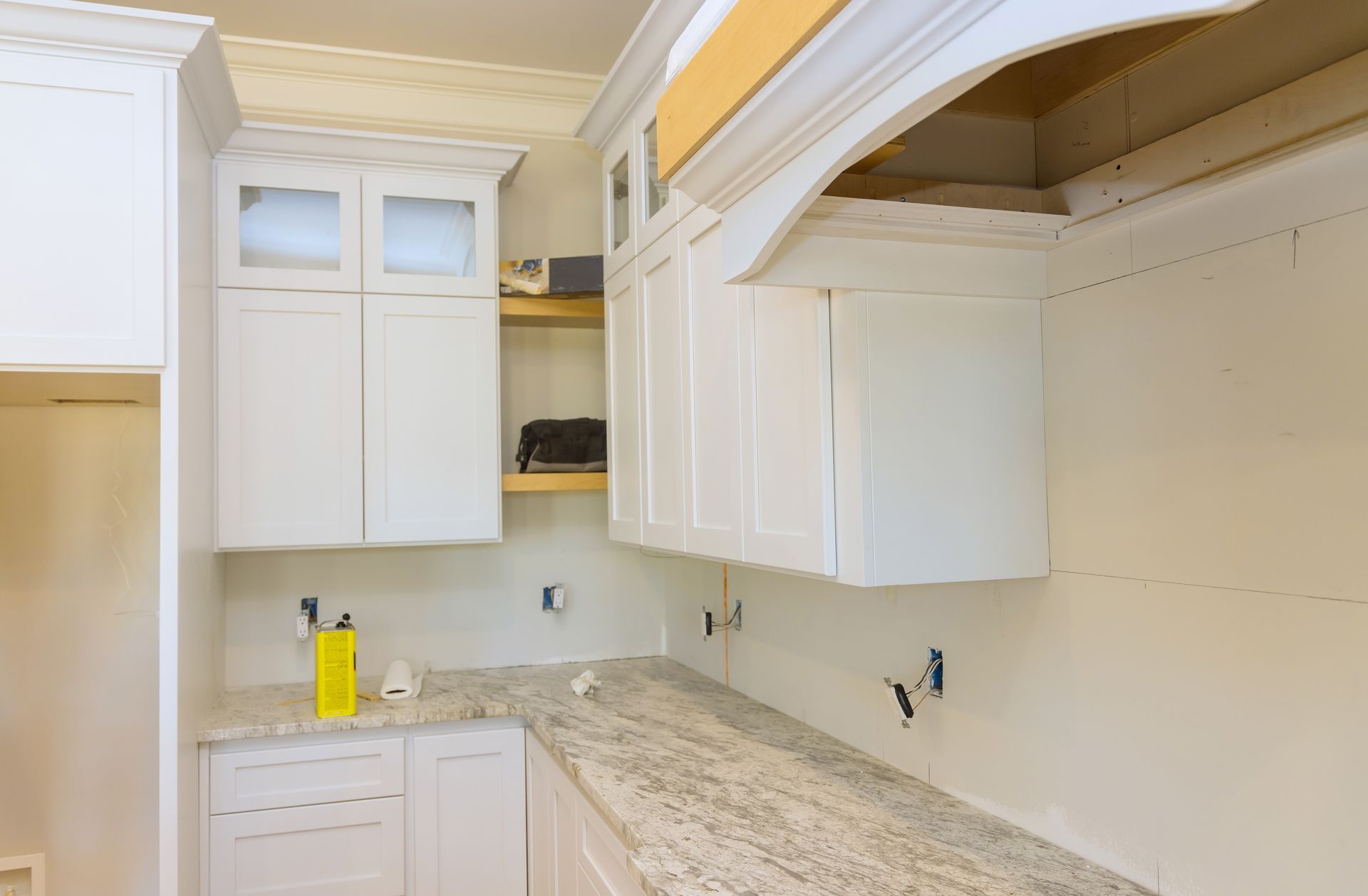 Empty kitchen with white cabinets, granite countertop, and an arched ceiling opening