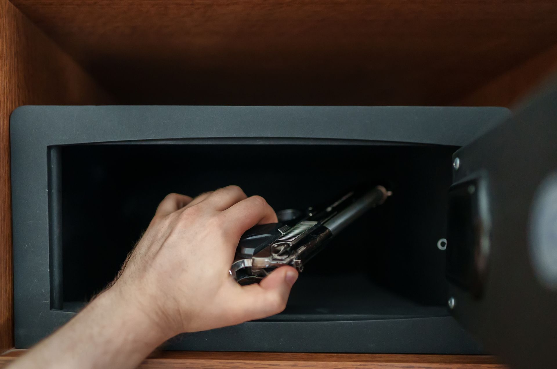Man putting the weapon in a gun storage safe. Man putting the weapon in a gun storage safe.