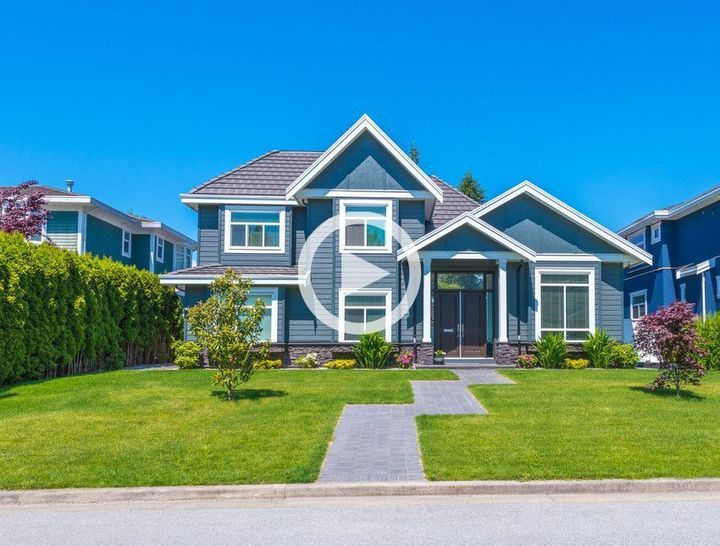 A large blue house with a lush green lawn in a residential neighborhood.