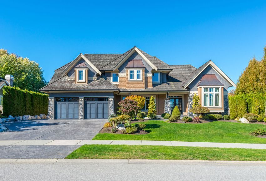 A large house with a large driveway in a residential neighborhood.