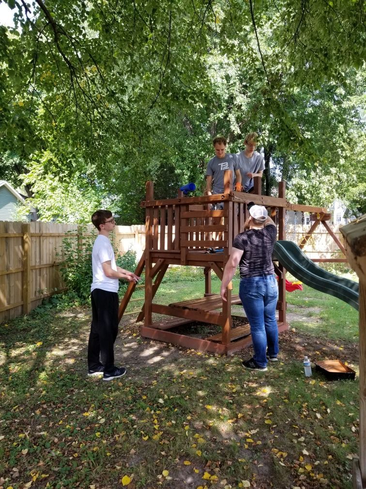 A group of people are working on a playground in a backyard.