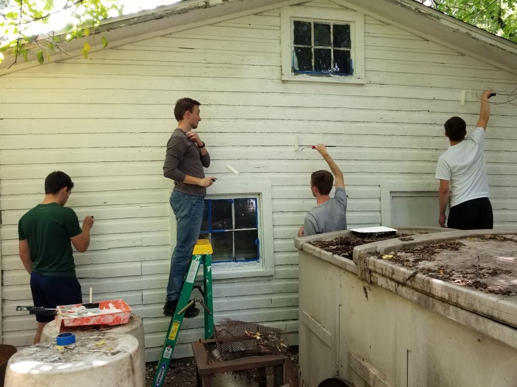 A group of people are painting a white building.