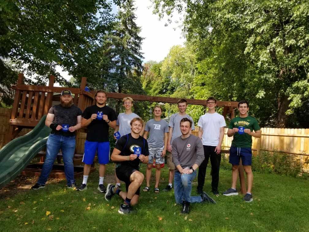 A group of young men are posing for a picture in a backyard.