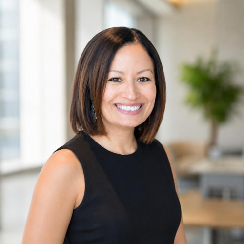 Smiling woman in a black sleeveless top in a bright office setting