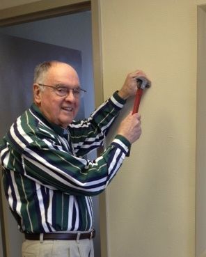 A man in a green and white striped shirt is holding a wrench