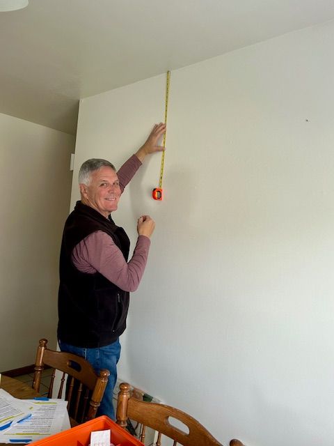 A man is measuring a wall with a tape measure