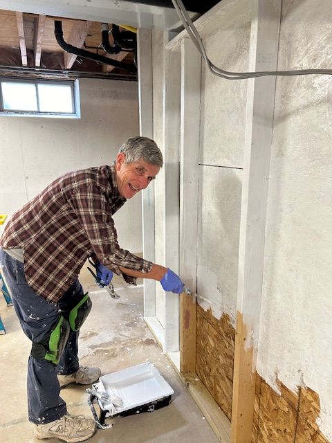A man is painting a wall in a basement.