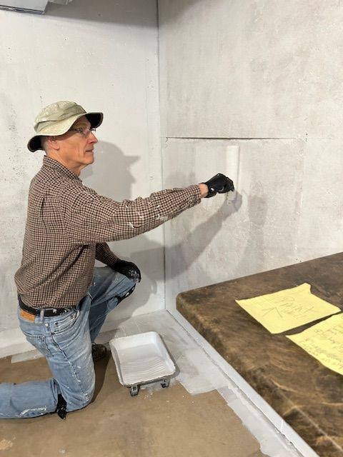 A man is kneeling down and painting a wall.