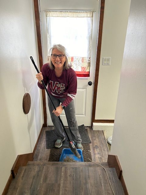 A woman is cleaning the floor with a mop in a hallway.