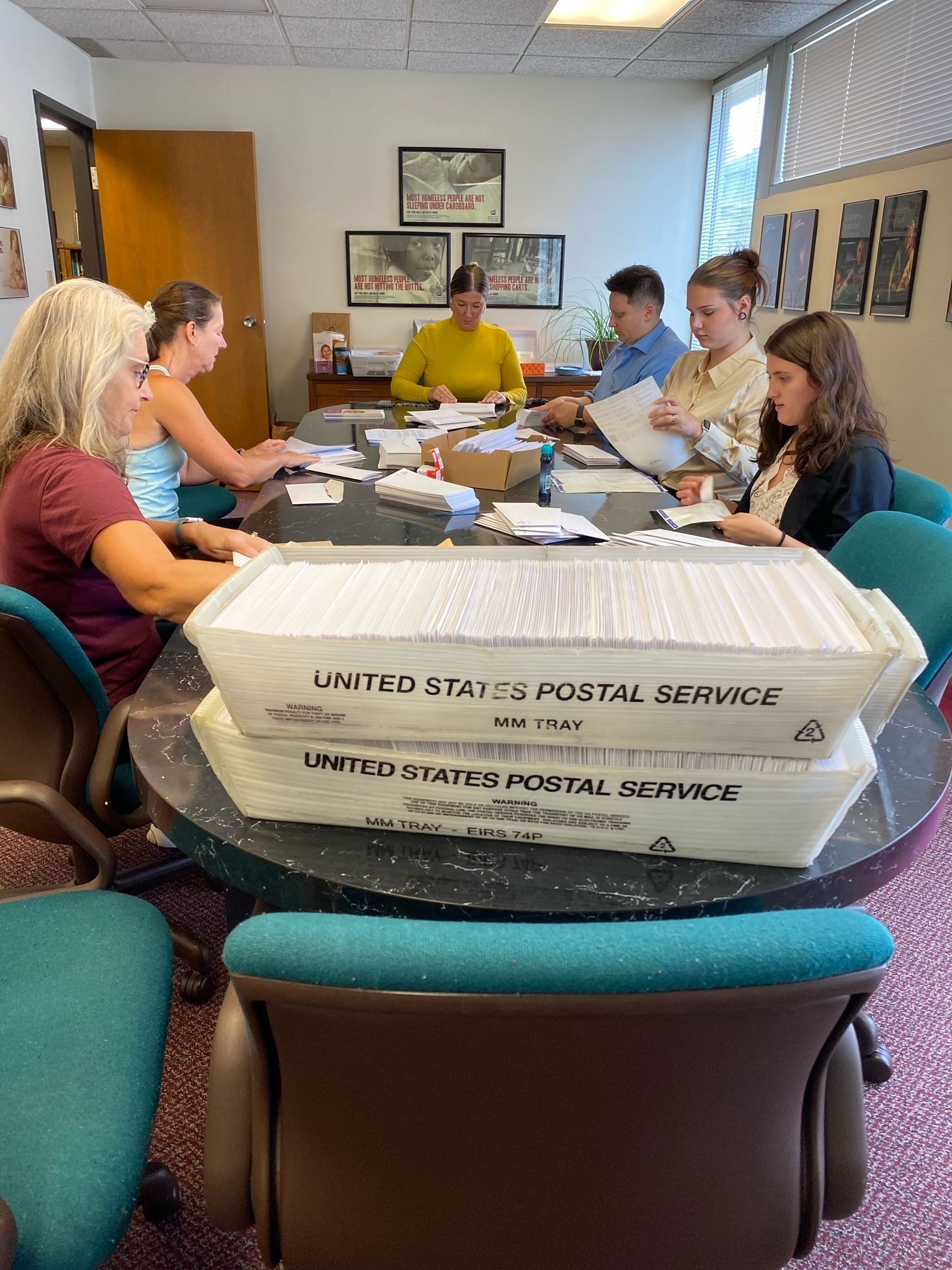 A group of people are sitting around a table with boxes on it.