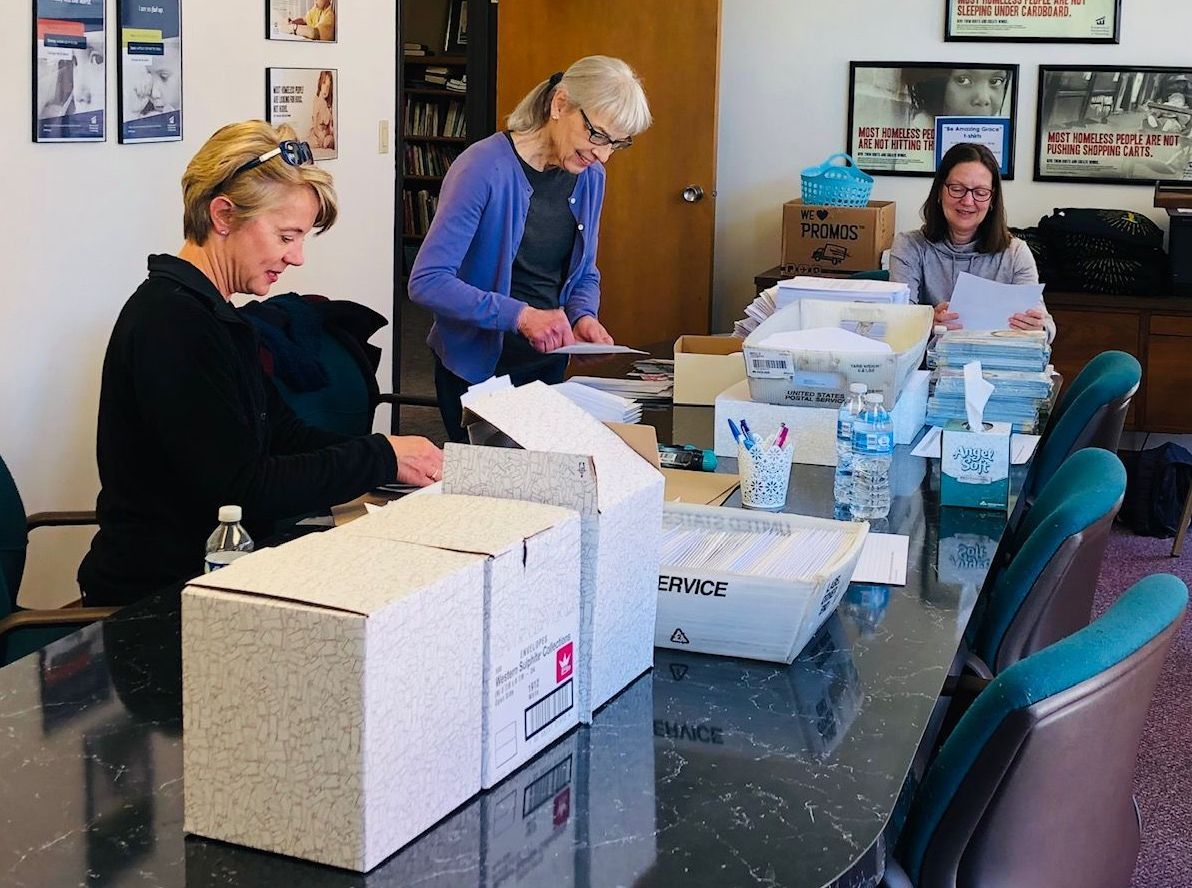 A group of women are sitting around a table with boxes on it.