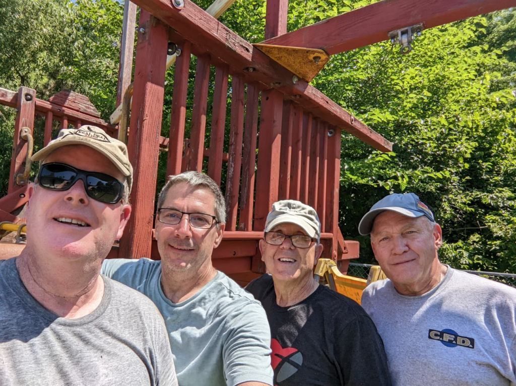 A group of men are posing for a picture in front of a playground.