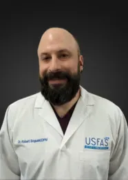 Man in white lab coat with beard, smiling, dark background,