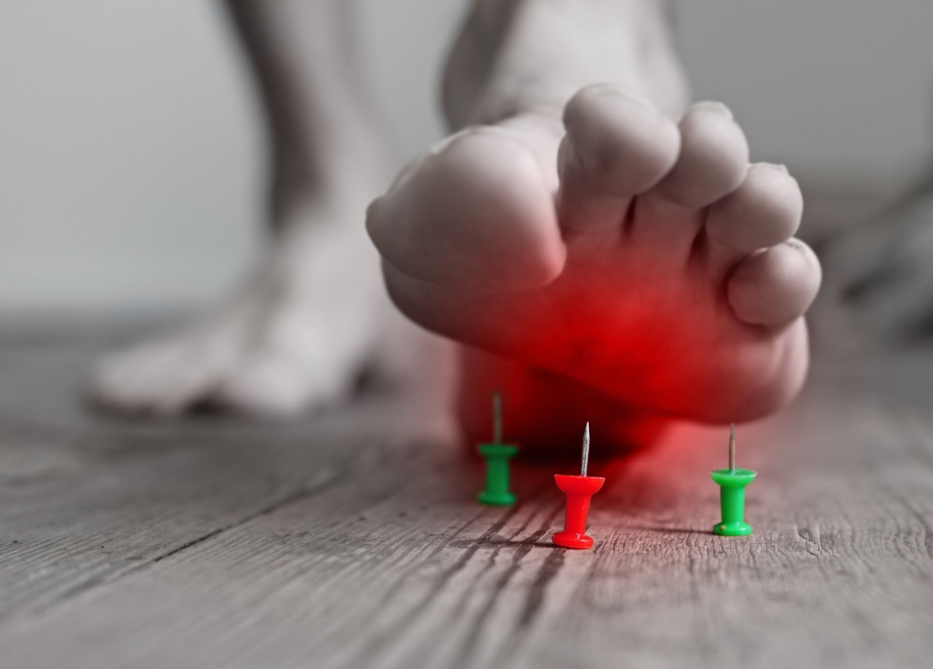 Foot about to step on push pins; highlighted red for pain.