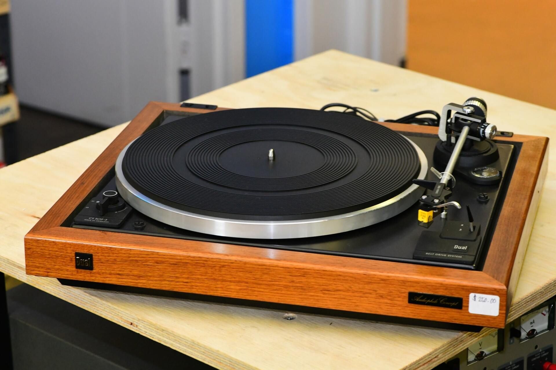 Wooden turntable record player with black platter and tonearm on a table