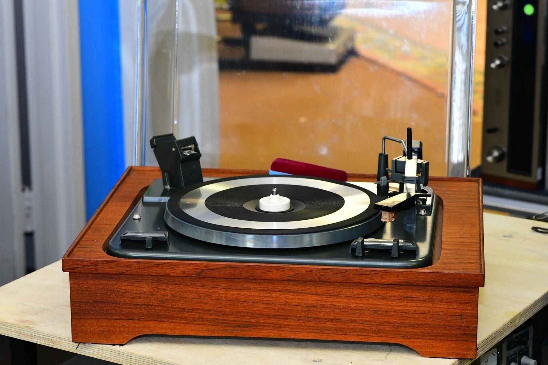 Wooden turntable with a black platter and tonearm on a tabletop indoors