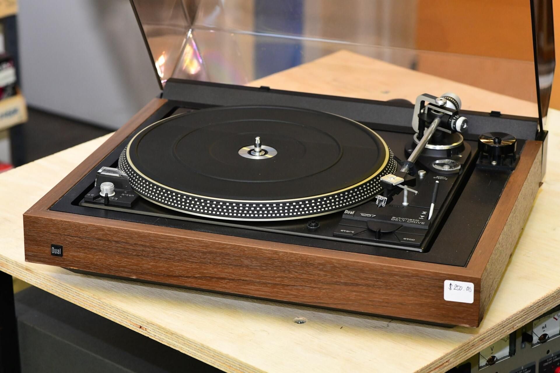 Vintage turntable record player with wooden base and clear dust cover open on a table