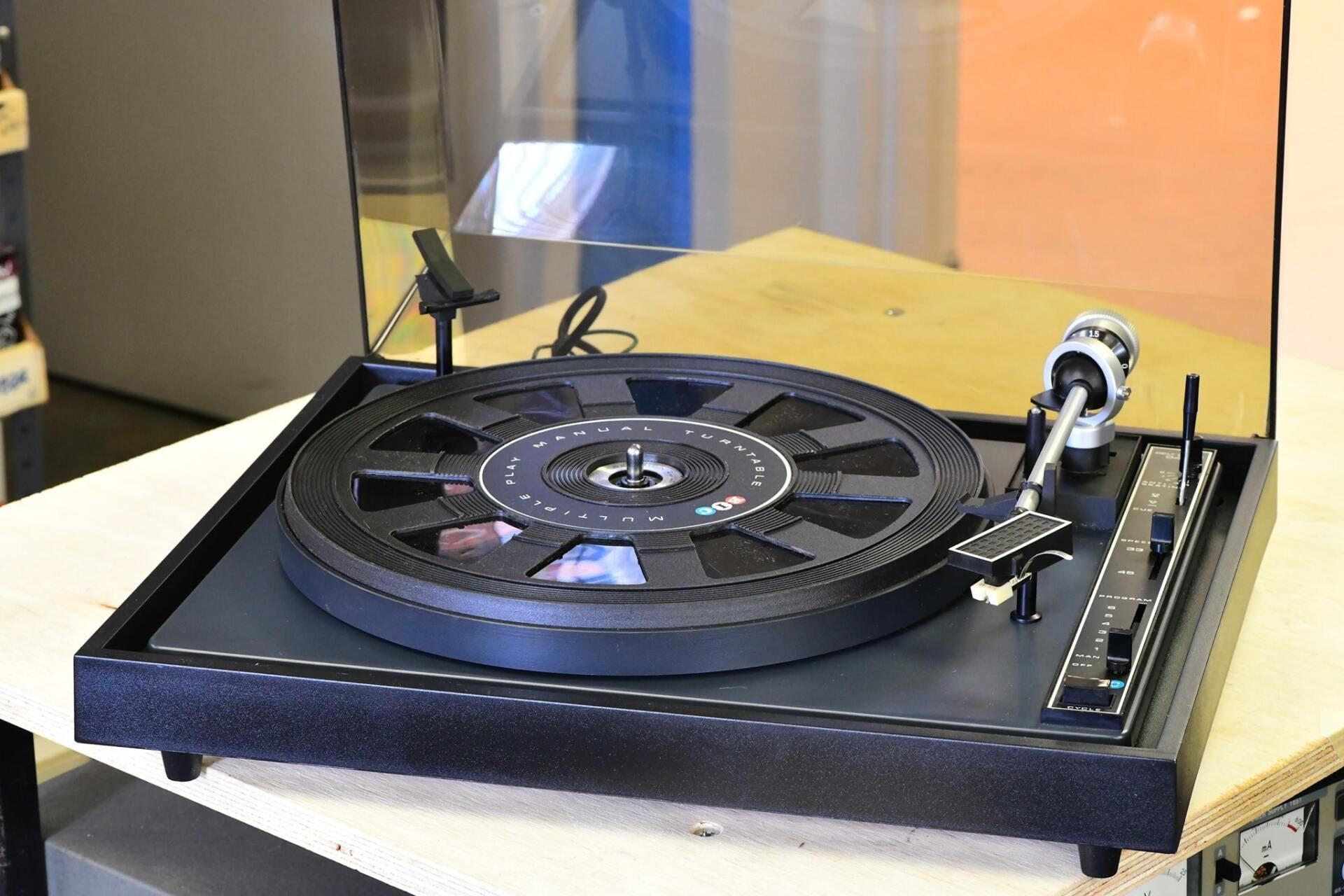 Vintage turntable record player on a table with a clear dust cover raised open