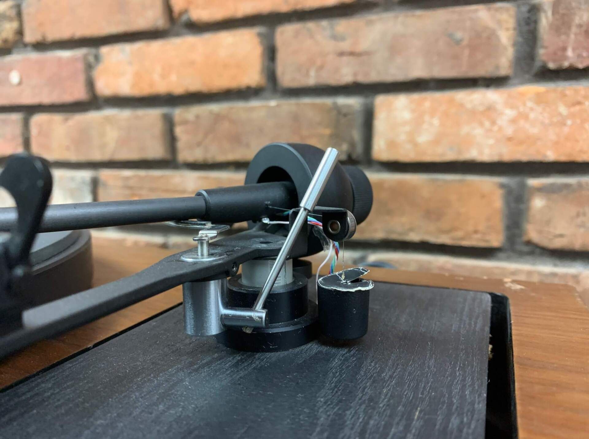 Small black model aircraft on a dark table, with a brick wall background.