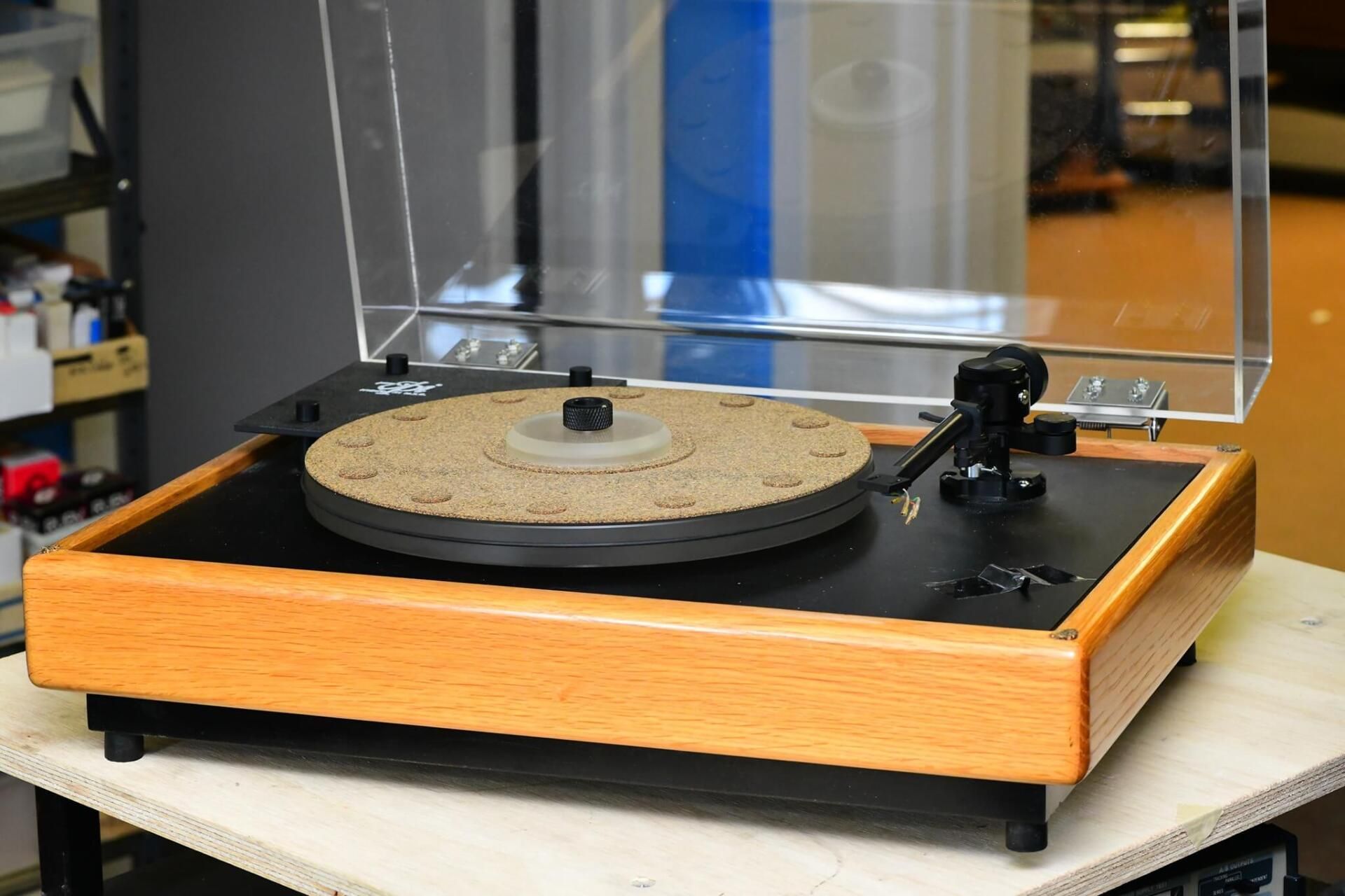 Vintage turntable with clear dust cover and wooden base on a table