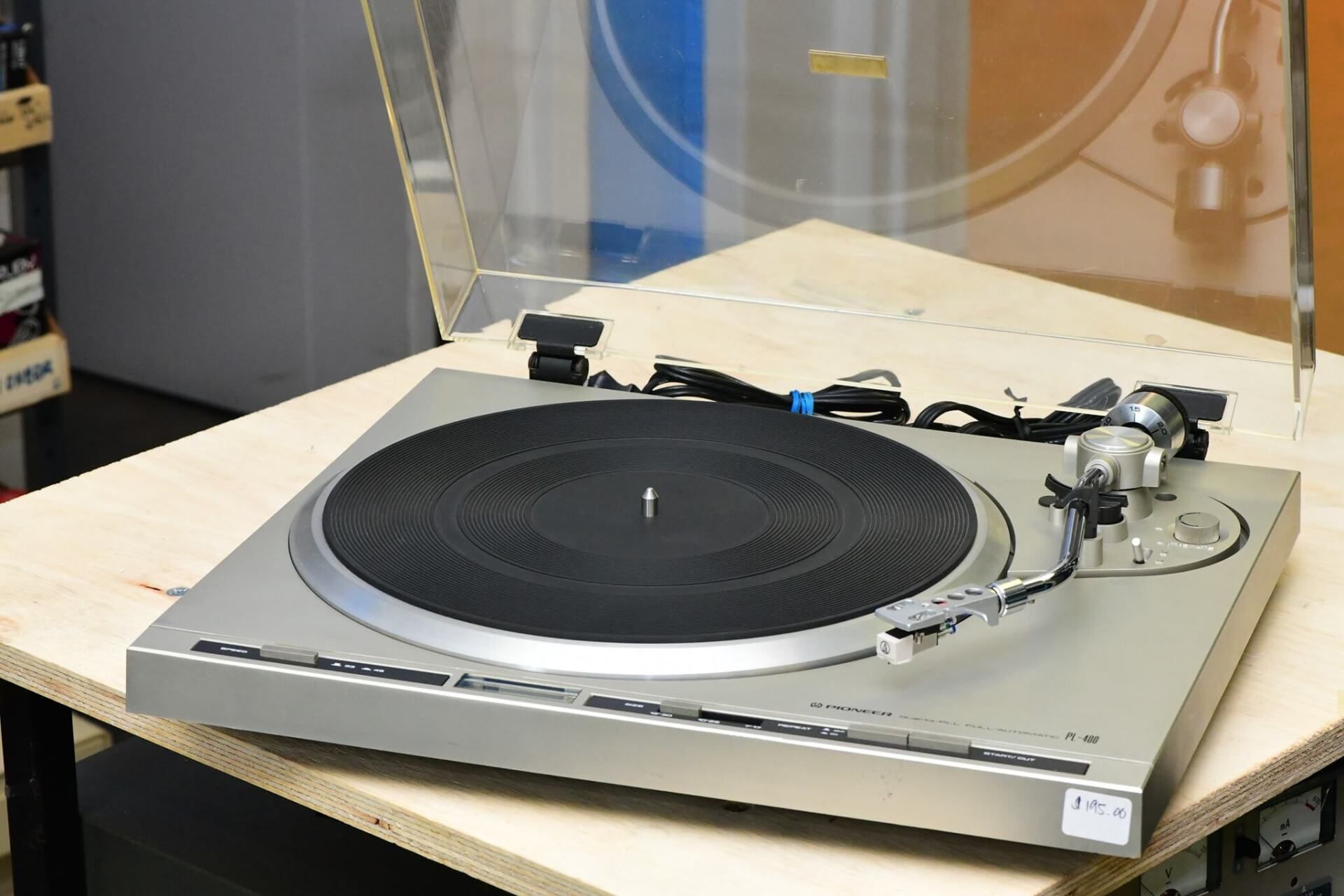 Silver turntable with black platter on a table in a workshop or studio setting