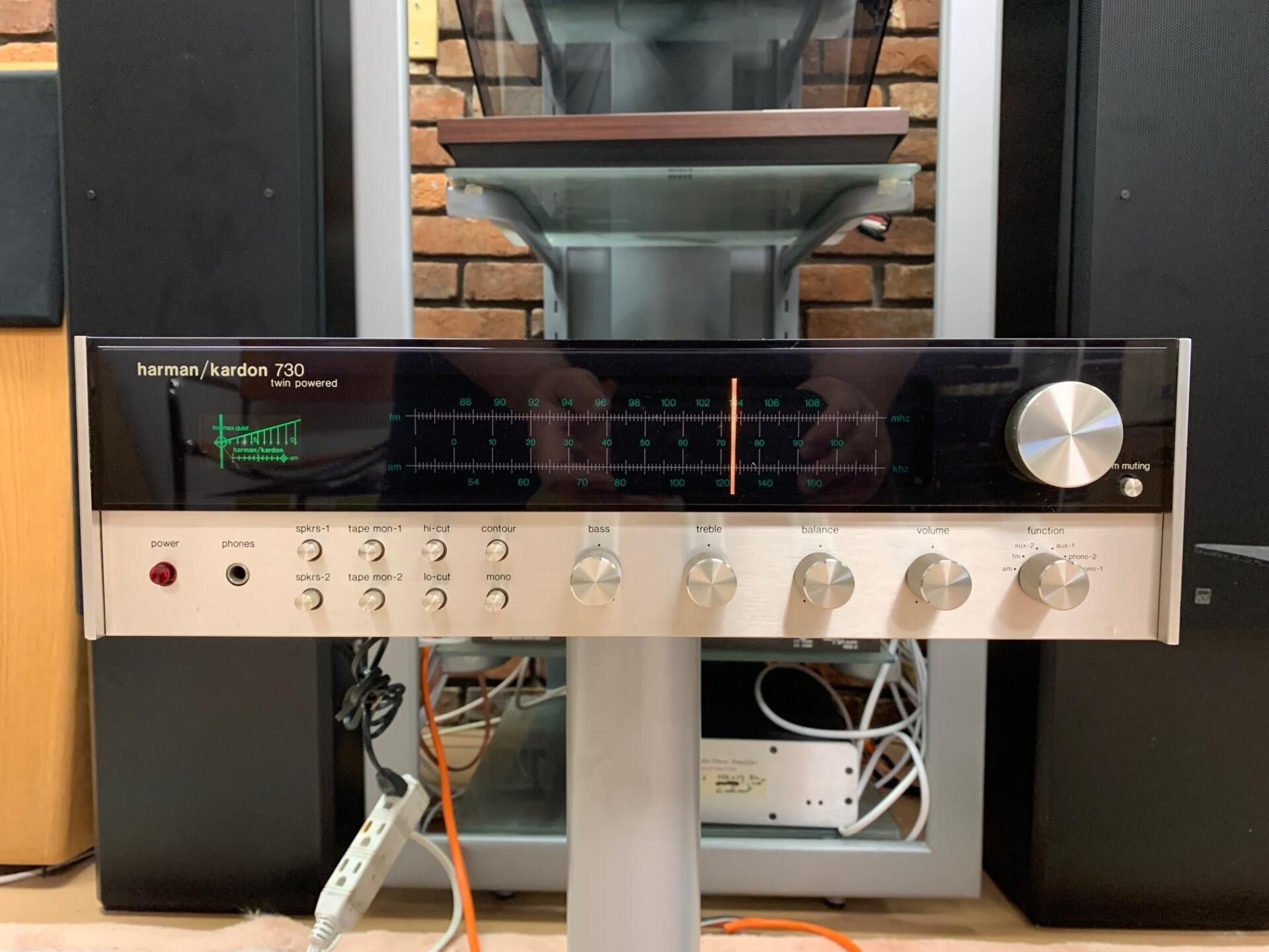 Vintage stereo receiver with silver knobs and black display on a shelf under a window
