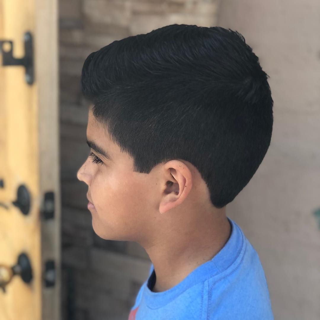 A young boy in a blue shirt is standing in front of a door
