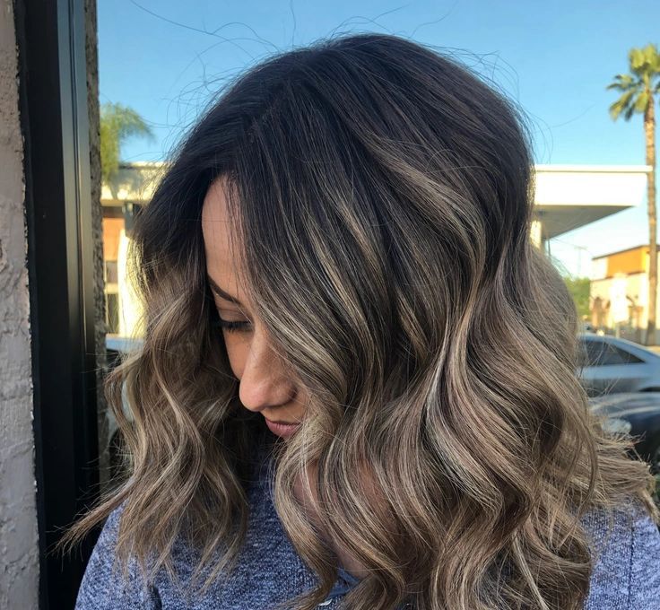 A woman with long wavy hair is wearing a blue shirt.