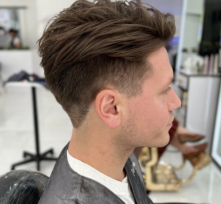 A man is sitting in a chair with his hair cut in a salon.
