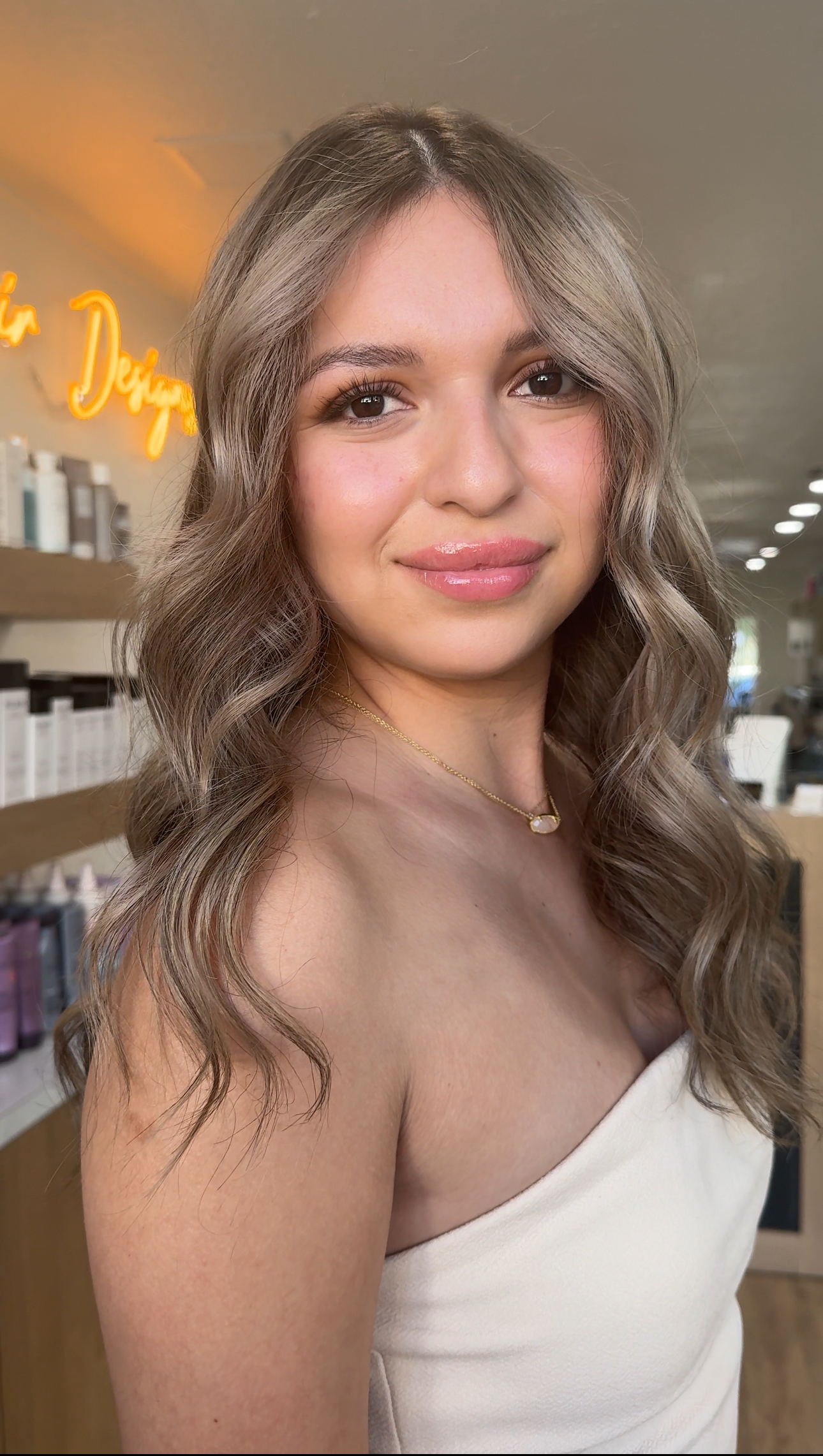 The woman is wearing a white strapless top and a necklace.