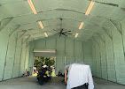 A motorcycle is parked inside of a garage with a ceiling fan.